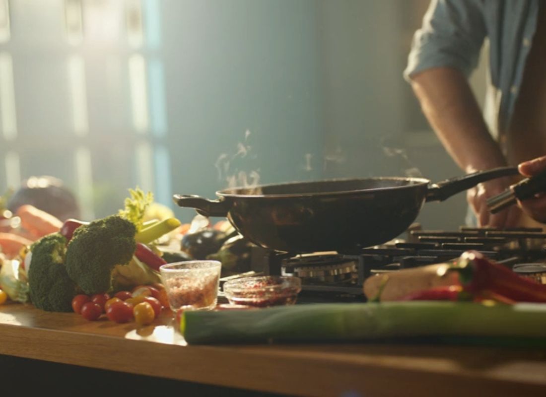 muškarac griluje povrće u tiganju