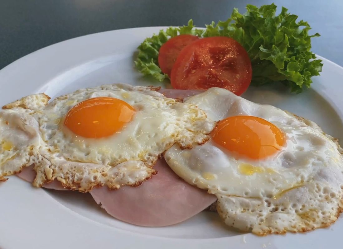 tanjir na kom su dva pržena jaja, salata i malo salame